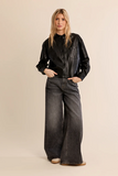 woman in cropped leather jacket and washed black jeans against a white background