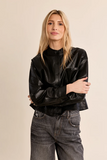 woman in cropped leather jacket against a white background