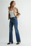 woman in flare jeans and beige jacket against a white background