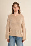 Woman wearing a beige sweater and blue jeans on a beige background