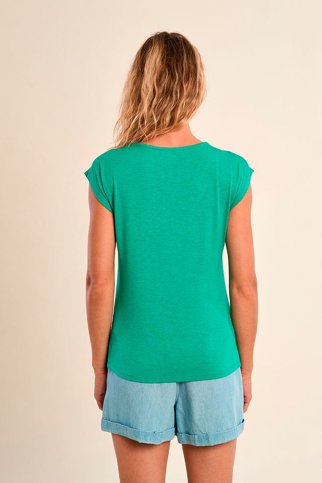 Woman wearing a green top and light blue shorts on a beige background