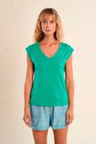 Woman wearing a green top and light blue shorts on a beige background