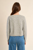 back of a girl wearing a grey cardigan and jeans against a white background