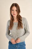 girl wearing a grey cardigan and jeans against a white background