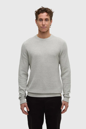 Man wearing a gray sweater and black pants on a white background