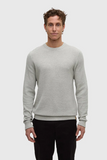 Man wearing a gray sweater and black pants on a white background