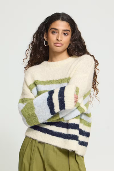 woman in horizontal striped sweater with arms crossed against white background