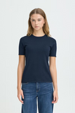 Woman wearing a navy blue t-shirt and jeans on a light gray background