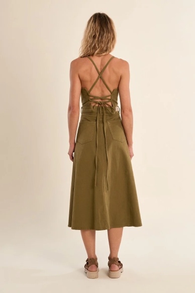 Woman wearing a green dress with criss-cross straps on a beige background