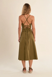 Woman wearing a green dress with criss-cross straps on a beige background