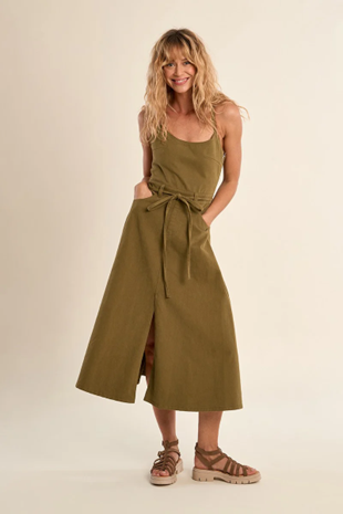 Woman wearing a green dress with a belt on a beige background