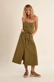 Woman wearing a green dress with a belt on a beige background