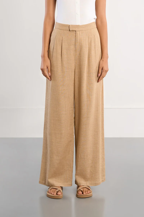 Person wearing beige wide-leg pants on a plain background