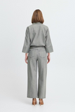 Person wearing a gray checkered shirt and wide-leg jeans on a white background