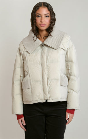 woman in cream puffer coat against white background