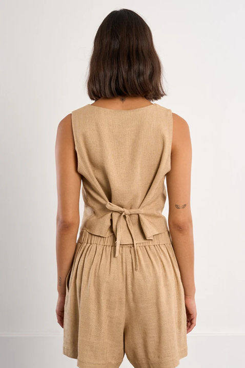 Woman wearing a beige sleeveless top and shorts set on a white background