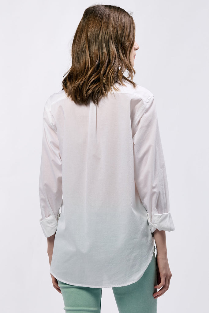 Woman wearing a white blouse with rolled-up sleeves on a plain background