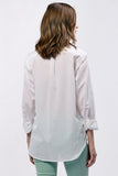 Woman wearing a white blouse with rolled-up sleeves on a plain background
