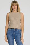 Woman wearing a beige sleeveless top and blue jeans on a plain background