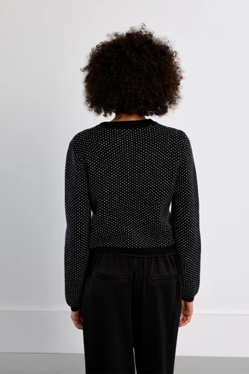 woman in black cropped sweater and black pants against white background
