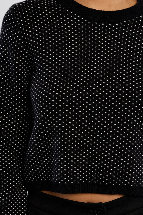 close up image of black sweater with white polka dots