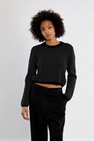 woman in black cropped sweater and black pants against white background