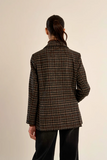 back of woman in plaid jacket against white background