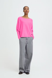 Person wearing a bright pink sweater and gray pants on a white background