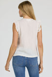 Woman wearing a white sleeveless top and blue jeans on a plain background