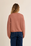back of woman in pink sweater and jeans against a white background