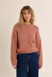 woman in pink sweater and jeans against a white background