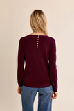 back of woman in plum sweater against white background