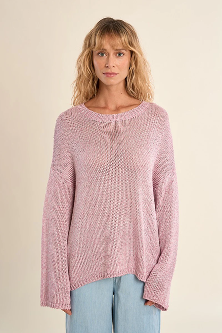 Woman wearing a pink knitted sweater against a beige background