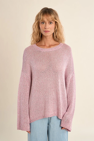 Woman wearing a pink knitted sweater against a beige background