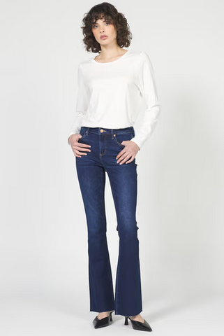 Woman wearing a white long-sleeve top and blue jeans on a white background