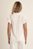 Woman wearing a white blouse with ruffled sleeves on a beige background