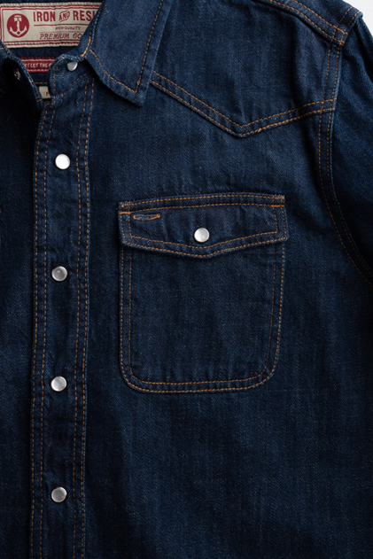 Close-up of a dark blue denim shirt with a pocket and buttons.