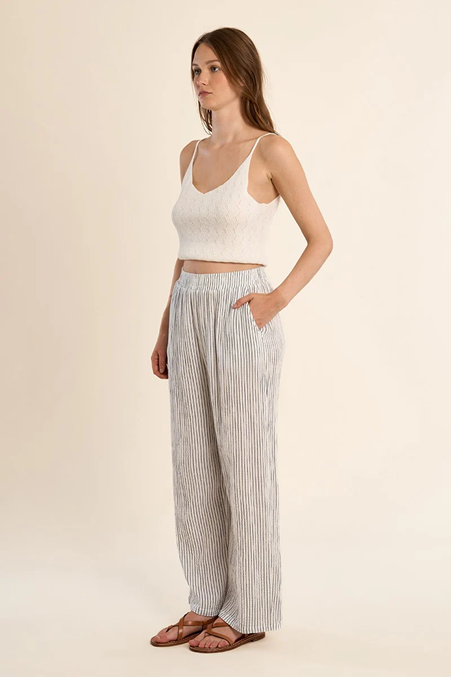 Woman wearing a white top and striped pants on a beige background