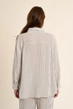 Person wearing a striped shirt and pants on a beige background