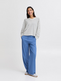 woman in blue and white striped top and blue jeans against white background
