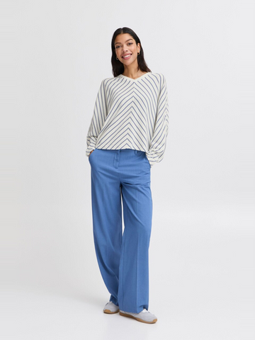 woman in blue and white striped top and blue jeans against white background