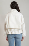 Person wearing a white jacket and blue jeans on a plain background
