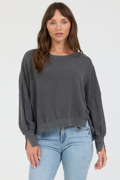 Woman wearing a dark gray sweatshirt and light blue jeans on a white background