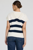 Woman wearing a white and navy striped sweater with a plain background