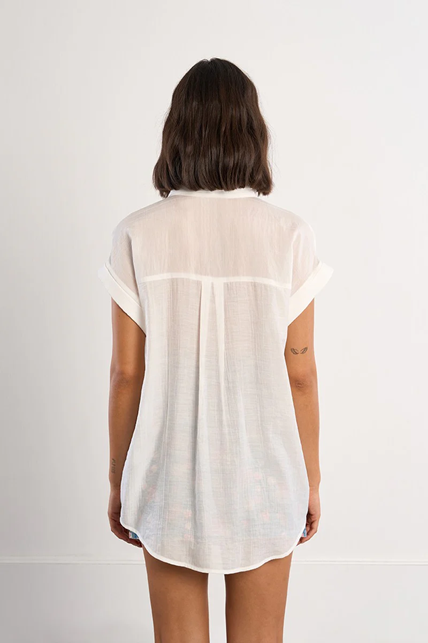 Person wearing a white sleeveless shirt against a plain background