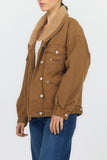 A woman wearing a brown corduroy jacket with a tan sherpa collar, paired with blue jeans, shown from the side against a light gray background.