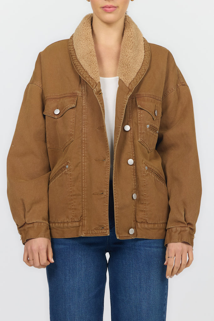 A model wearing a brown corduroy jacket with a tan sherpa collar, styled with a white top and blue jeans against a plain white background.