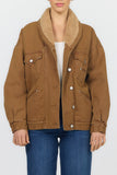 A model wearing a brown corduroy jacket with a tan sherpa collar, styled with a white top and blue jeans against a plain white background.