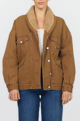 A model wearing a brown corduroy jacket with a tan sherpa collar, styled with a white top and blue jeans against a plain white background.