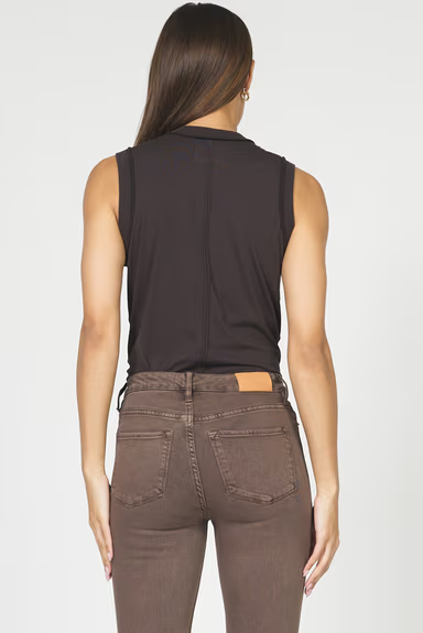 Woman wearing a black sleeveless top and brown pants on a white background